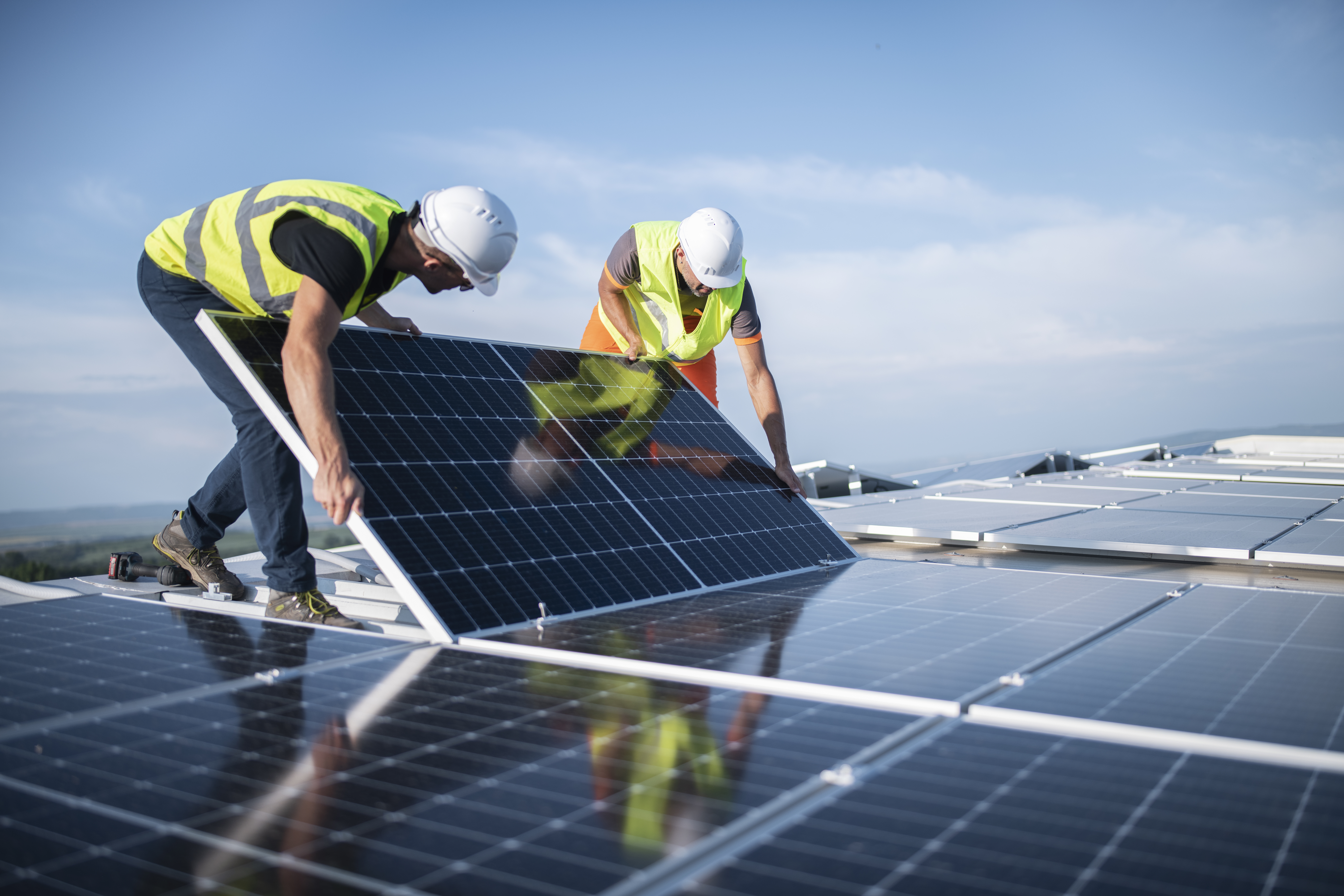 Zwei Arbeiter montieren Photovoltaik-Panel auf Dach