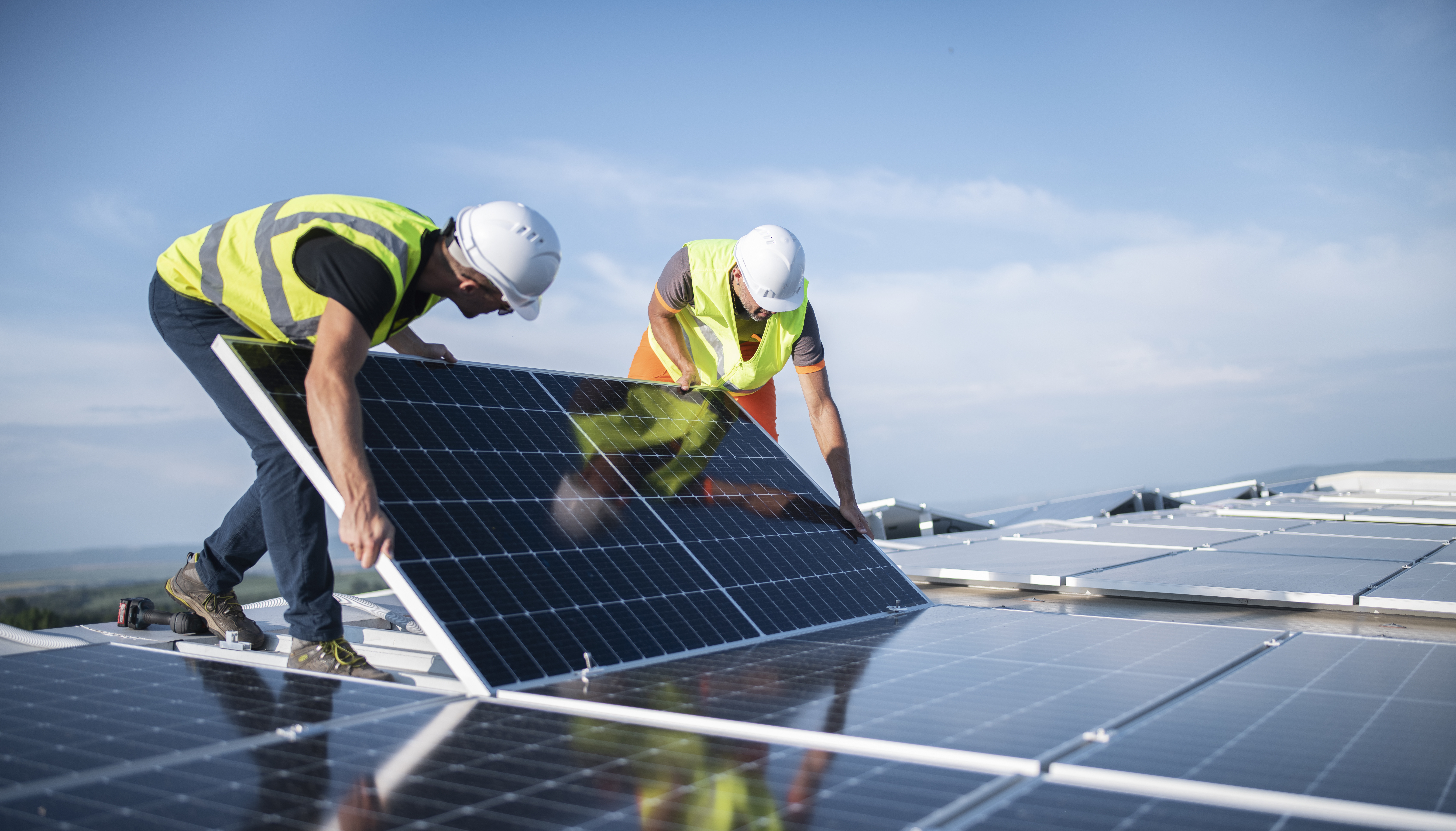 Zwei Arbeiter montieren Photovoltaik-Panel auf Dach