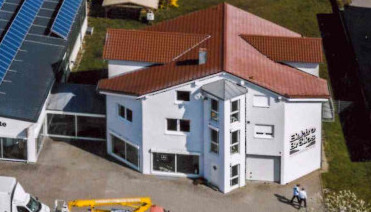 Firmebgebäude des Miele Partners Elektro BRÖLLOS mit Solaranlagen auf Dach und Showroom mit Waschmaschinen.